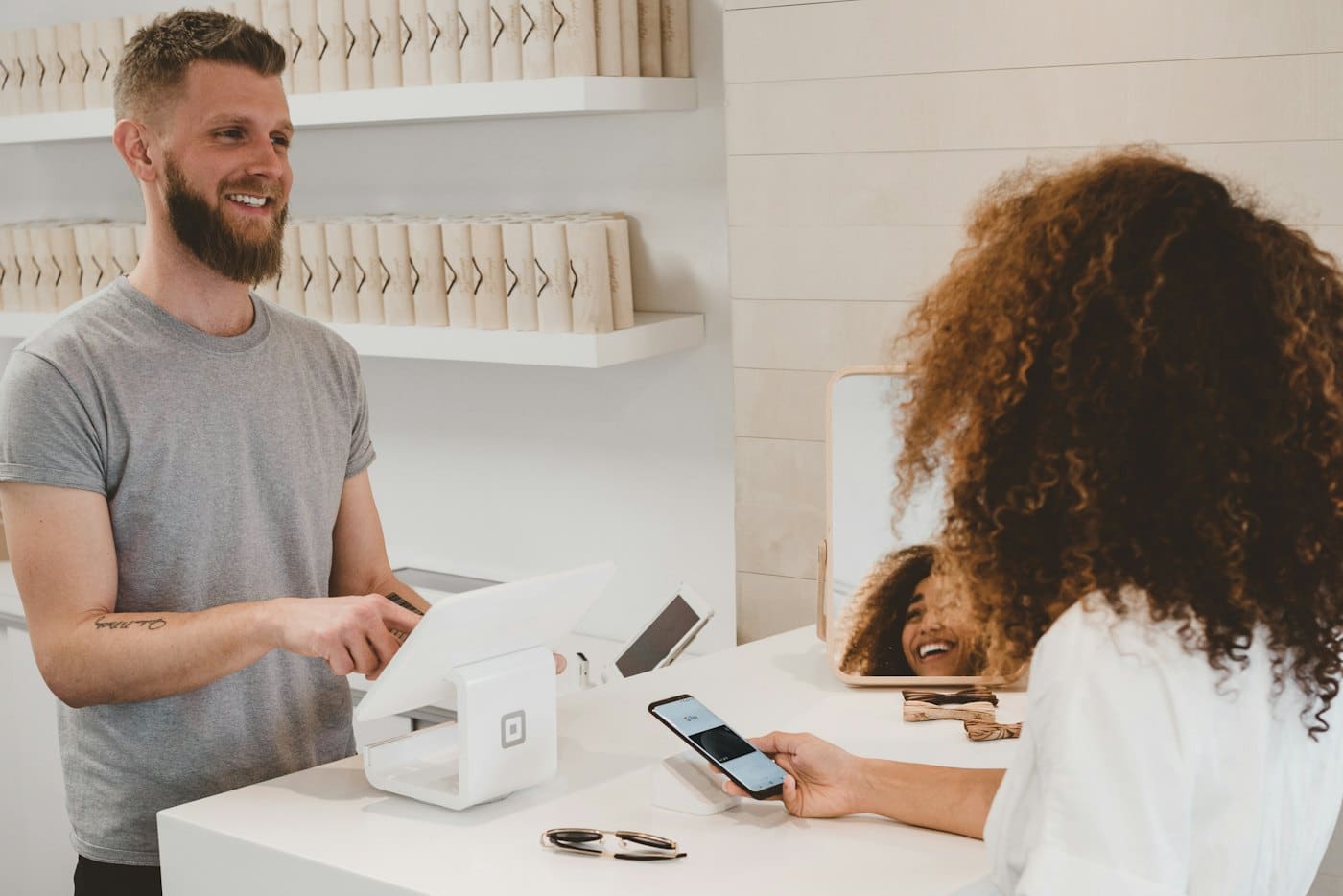 Shop owner serving a customer at a modern checkout counter