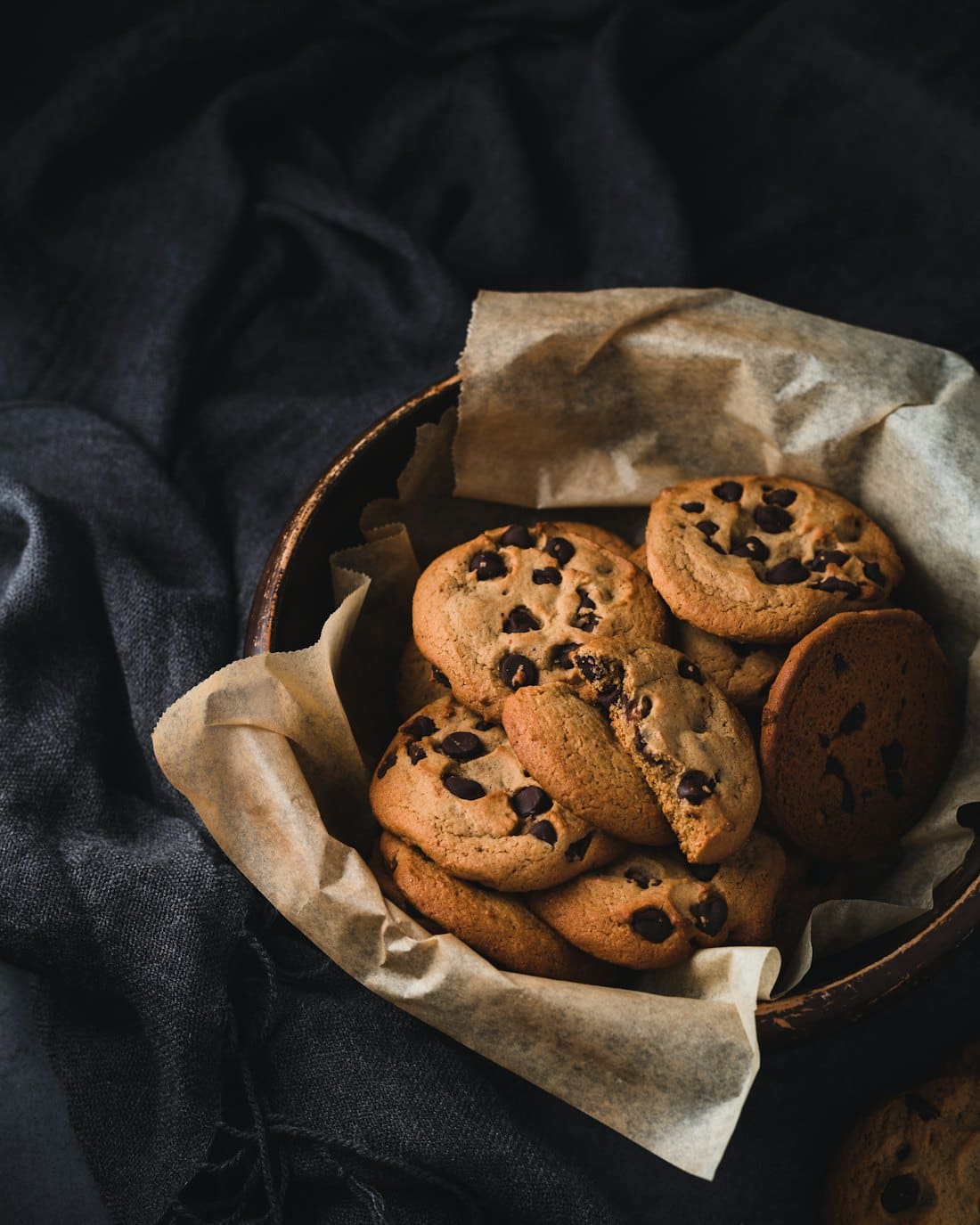 Chocolate chip cookies piled in a paper-lined bowl