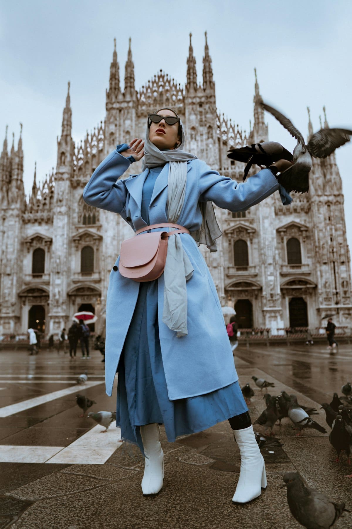 Woman in a powder-blue long coat in a cathedral square