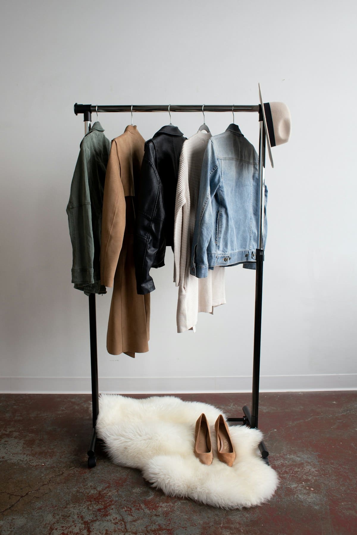 Minimal clothing rail with neutral jackets and a sheepskin rug