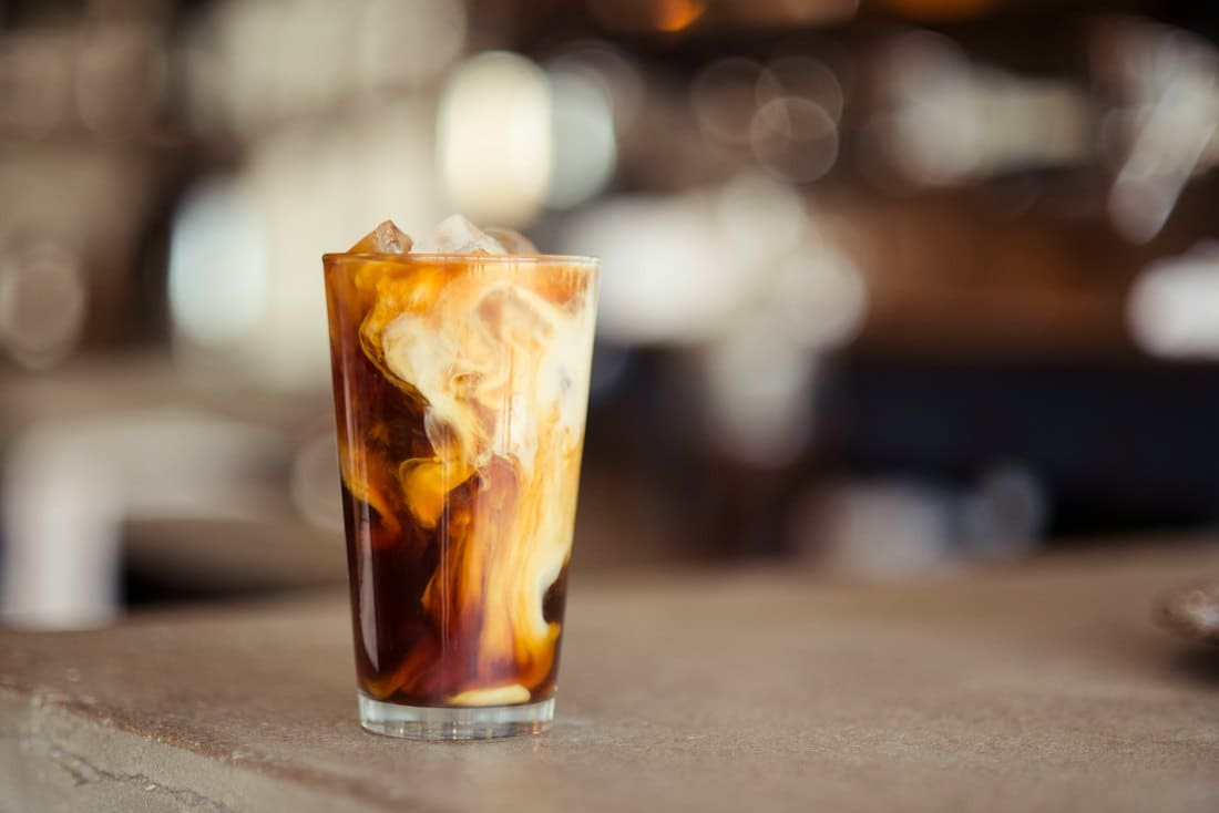 Iced coffee with cream swirling through a tall glass
