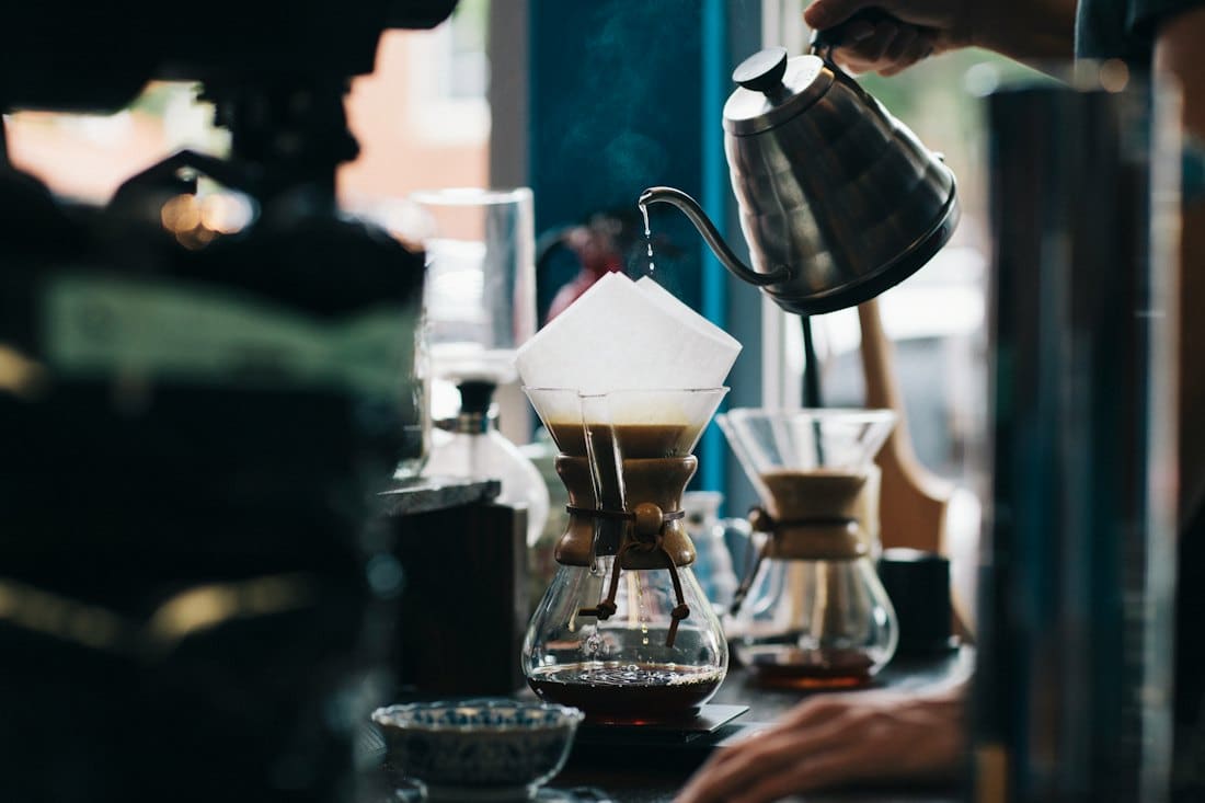 Hand pouring hot water over a pour-over coffee dripper