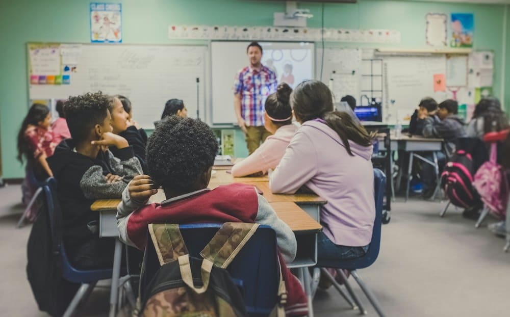 Students listening to a teacher in a bright classroom