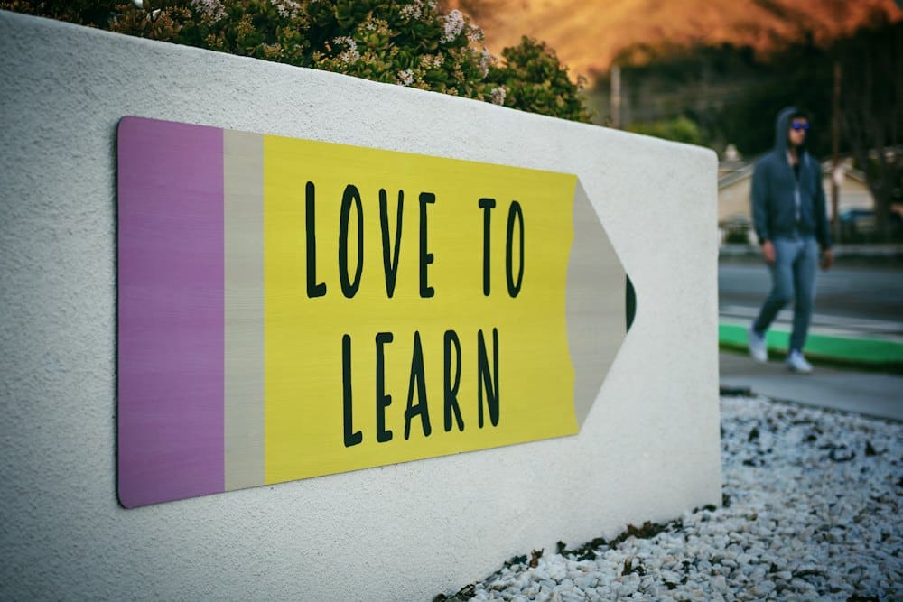 Pencil-shaped sign reading Love to Learn on a school wall