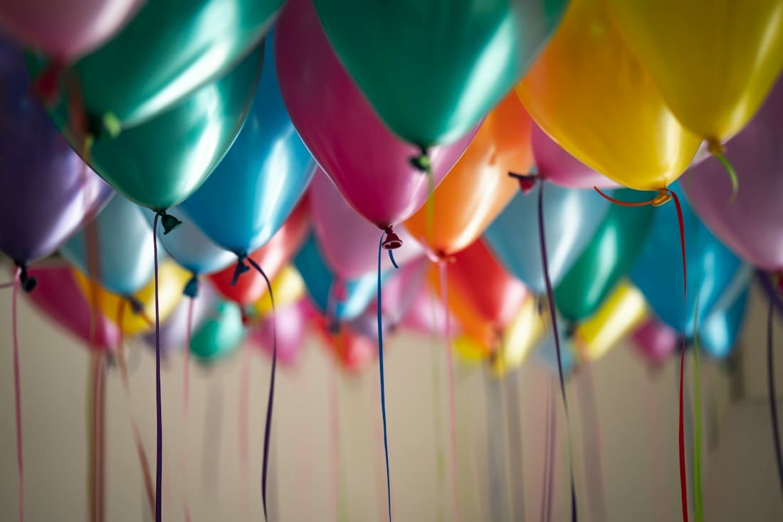 Ceiling filled with colourful helium balloons and trailing ribbons