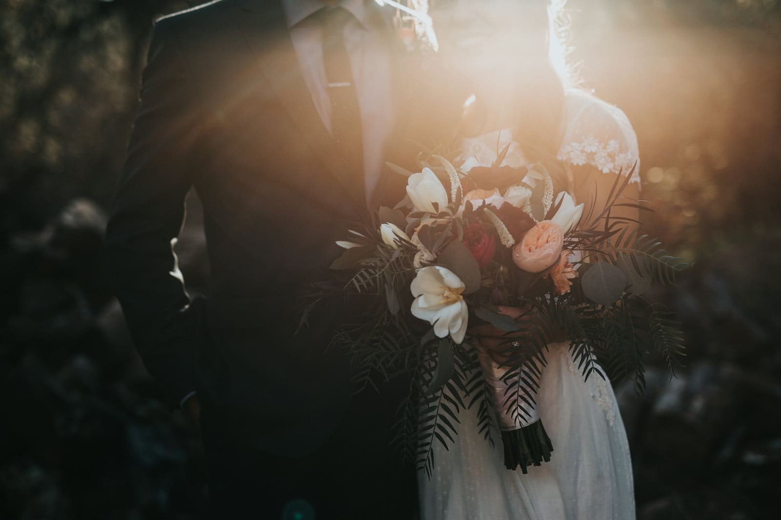 Bride holding a soft pink and ivory bouquet in warm evening light