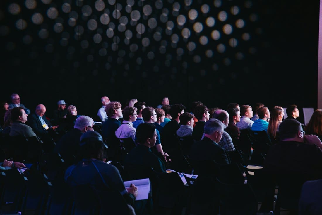 Audience seated in a darkened auditorium during a company keynote