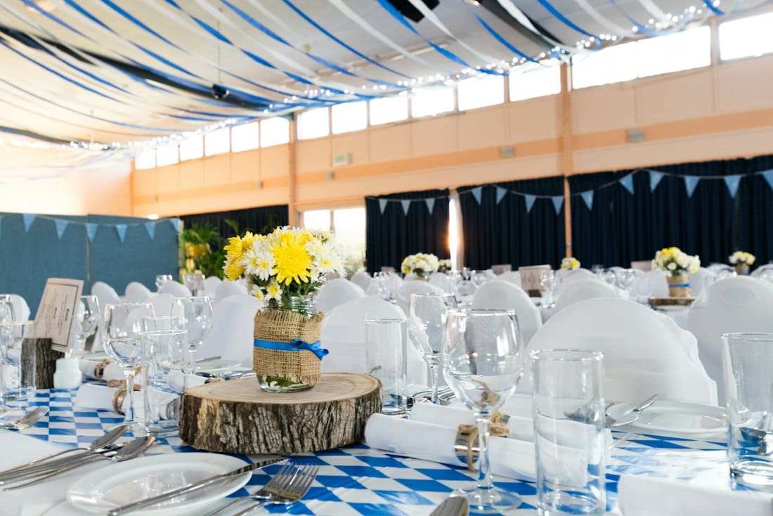 Marquee laid with white chairs, blue checked linens and yellow flower posies