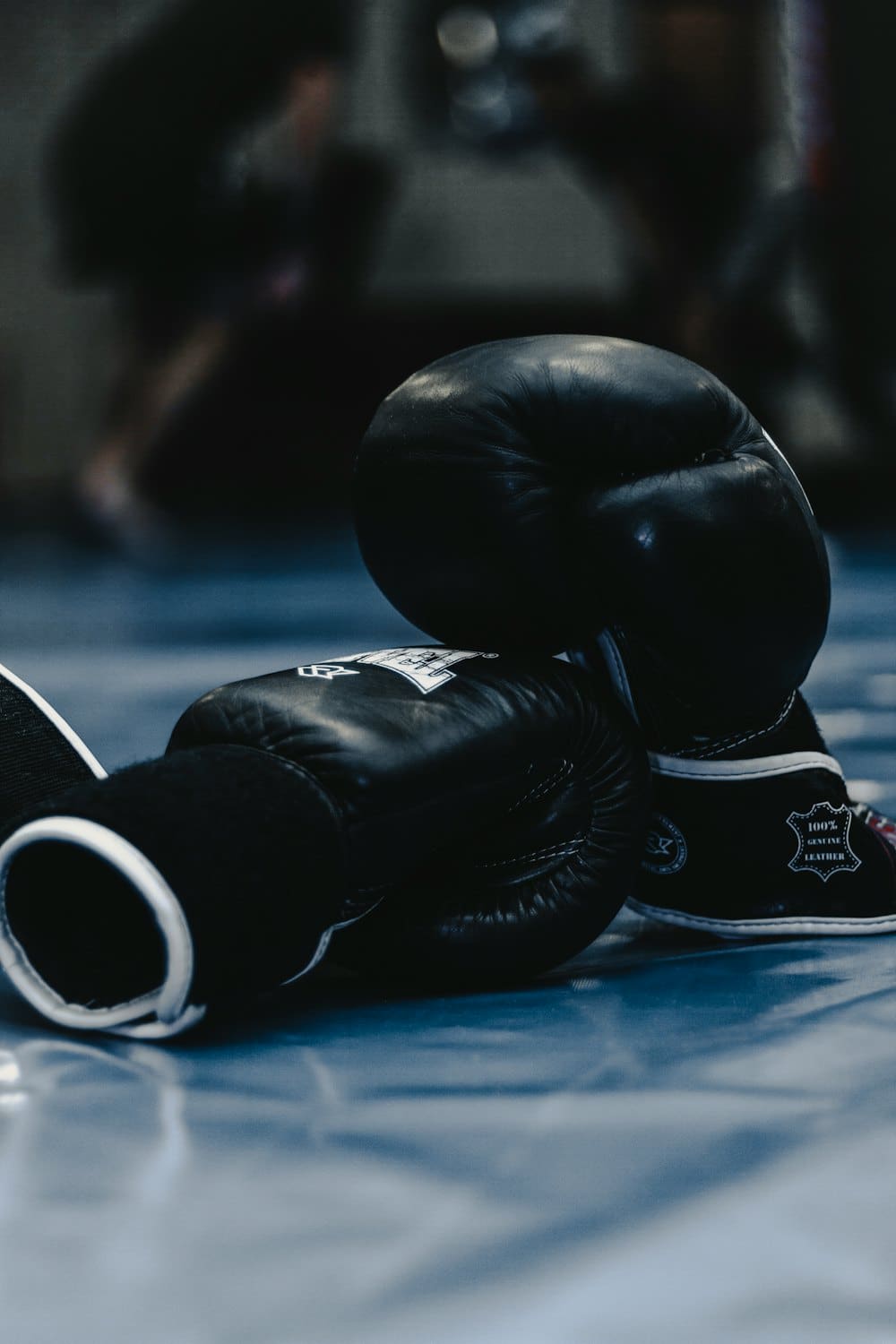 Pair of black boxing gloves resting on a gym floor