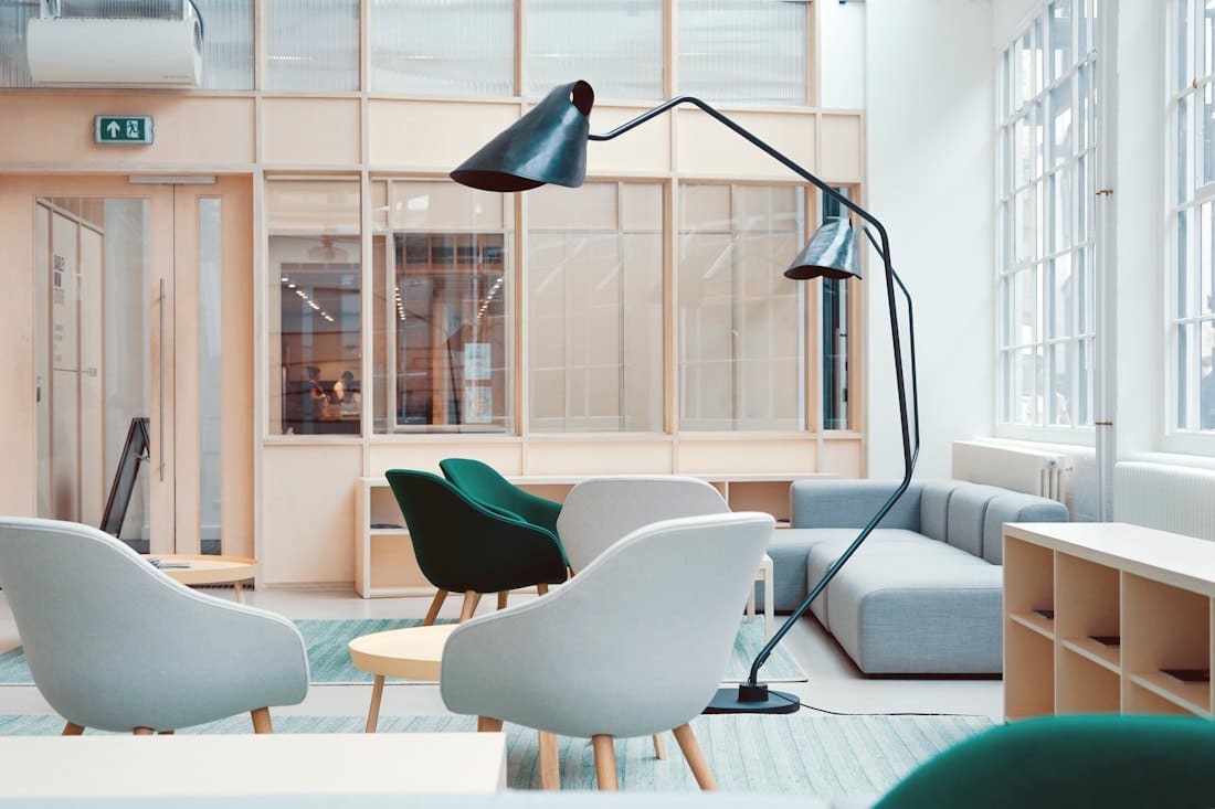 Airy office lounge with sculptural lamp and white chairs