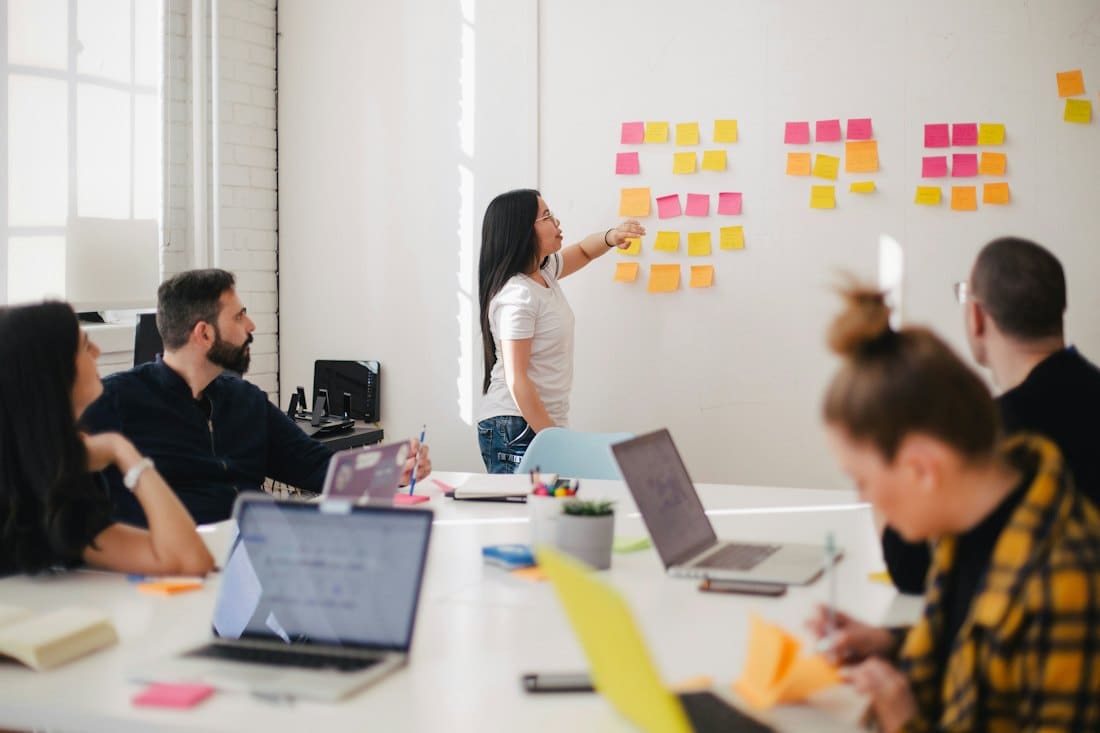 Team workshop with sticky notes on a whiteboard around a meeting table