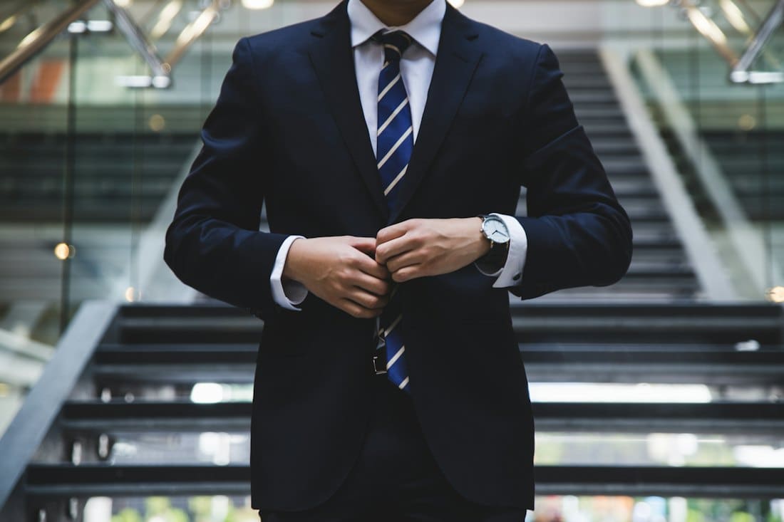 Consultant in a navy suit buttoning his jacket on an office staircase