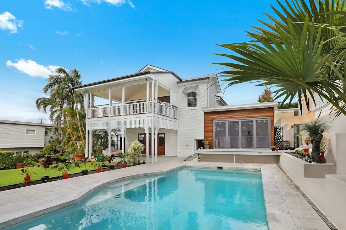 White villa with palm trees and a large swimming pool