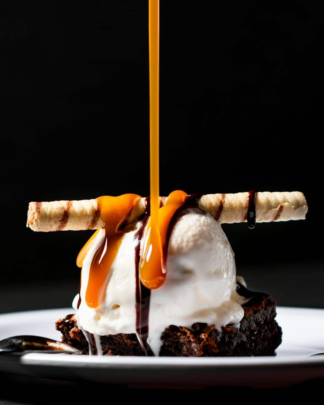 Caramel poured over vanilla ice cream with a crisp tuile