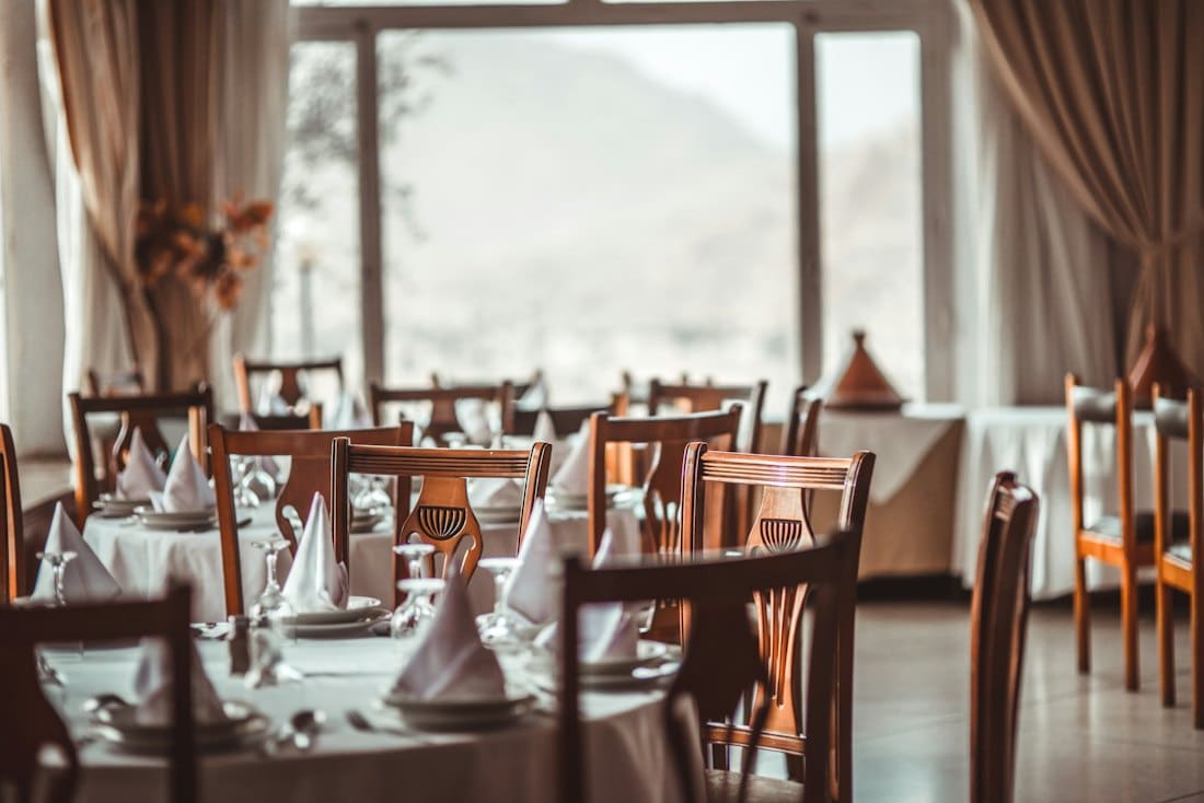 Private dining room with long table set with white linen and folded napkins