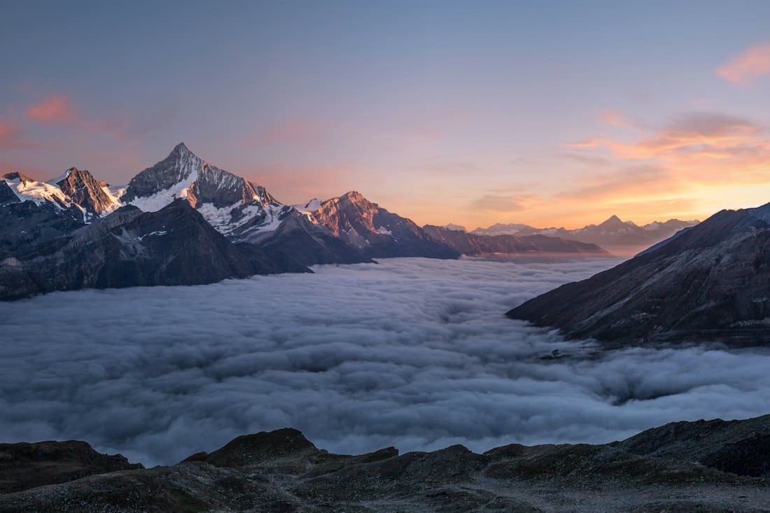 Snowy summits rising above a sea of clouds at dusk