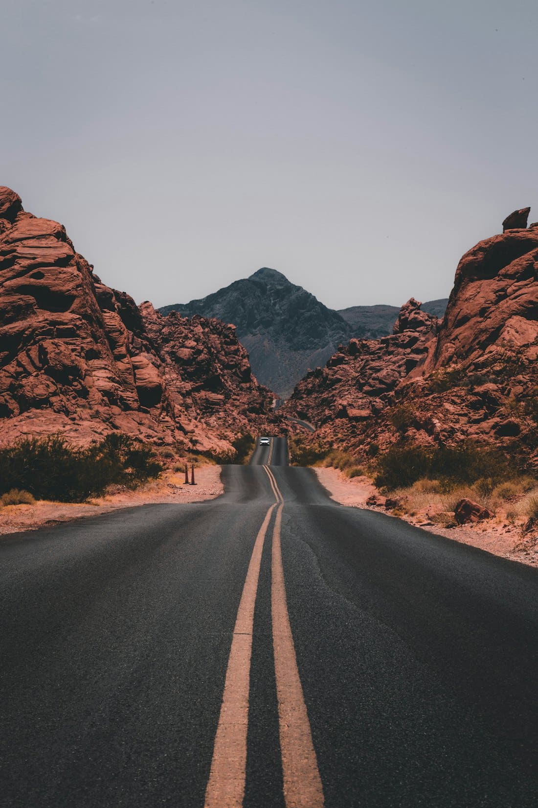 Empty desert highway leading between red rock canyons
